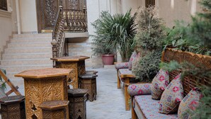 An outdoor seating area with ornate wooden furniture and a staircase.
