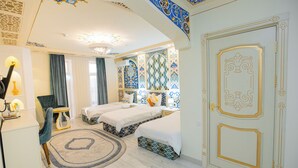 A hotel room with two beds, a desk, a chair, and a decorative rug.