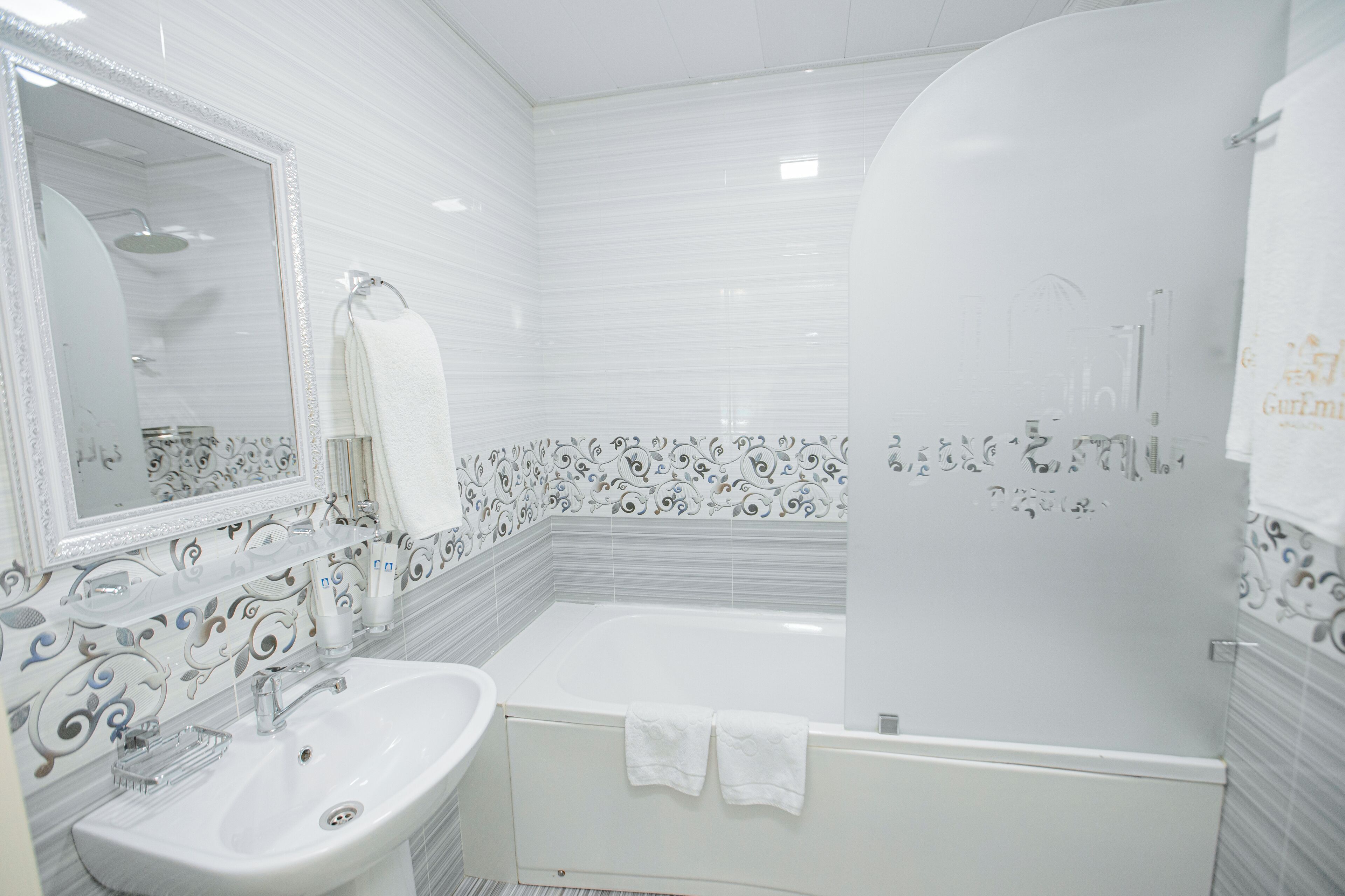 Un baño con lavamanos blanco, un espejo y una bañera.