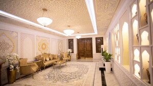 A luxurious room with a large ornate rug, a sofa set, and a chandelier.