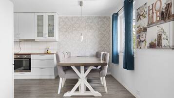 A modern kitchen with white cabinets, a wooden dining table, and blue curtains.