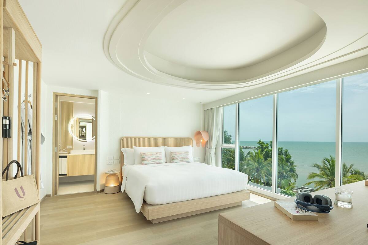 Une chambre moderne avec un grand lit, une coiffeuse et une vue sur l’océan.