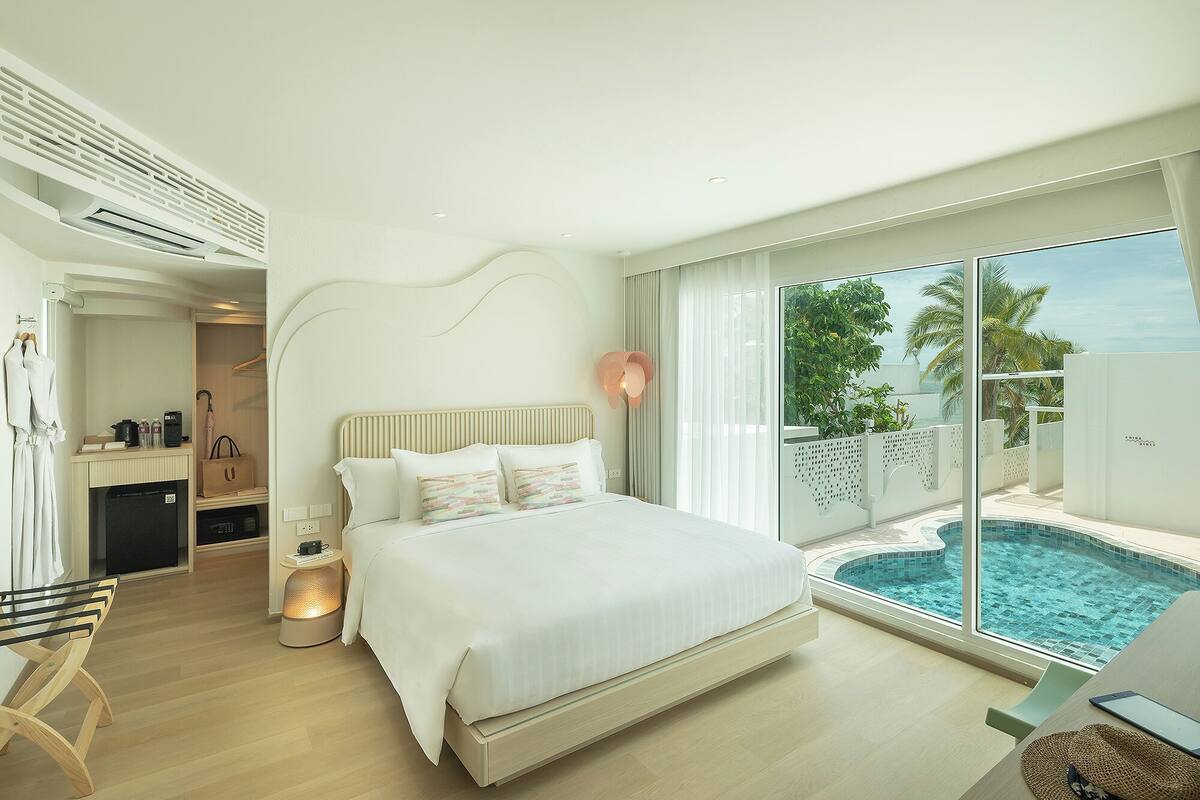 Une chambre d’hôtel moderne avec un grand lit, un bureau et une vue sur une piscine.