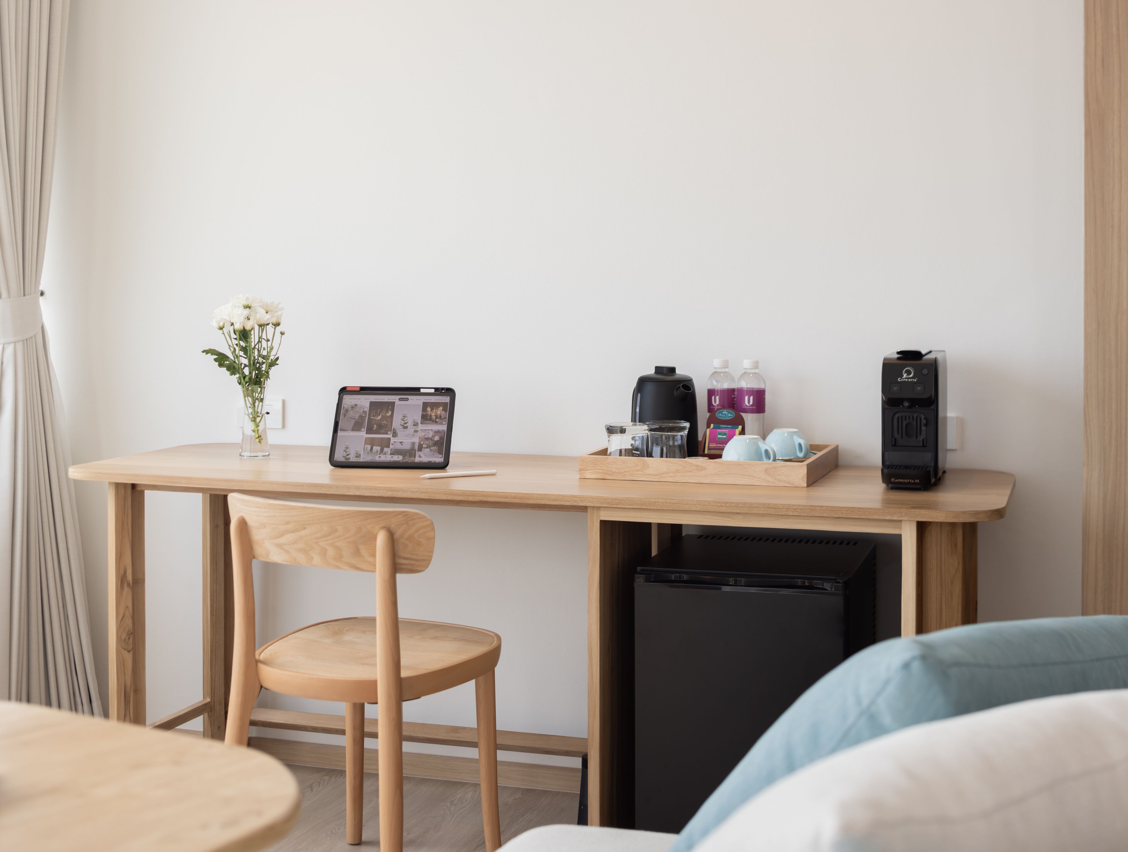A compact workspace with a laptop, coffee maker, and personal items on a wooden desk.