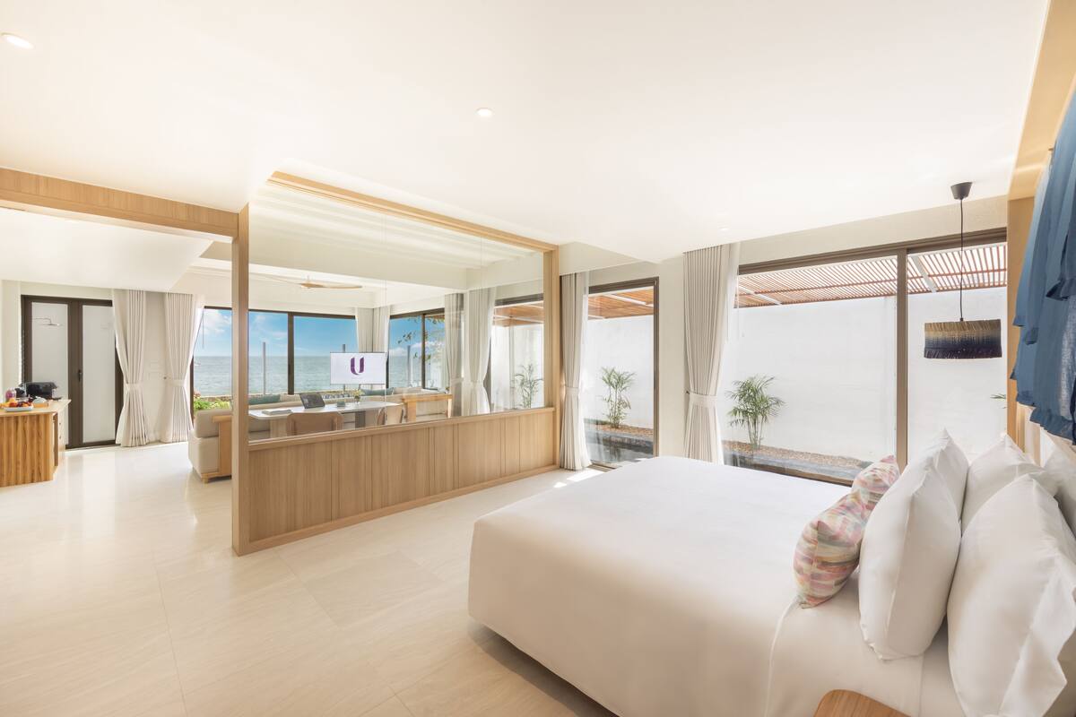 Une chambre d’hôtel moderne dotée d’un grand lit, d’un coin salon avec vue et d’une kitchenette séparée.