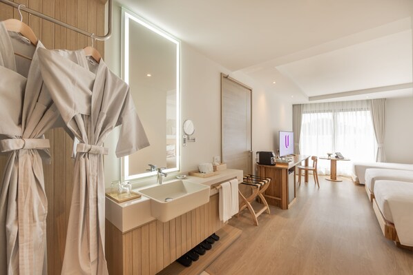 Una habitación de hotel moderna con un tocador de madera, un espejo grande, un televisor de pantalla plana, un escritorio con una silla y una cama.