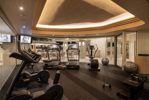 Un gimnasio moderno con cintas de correr, elípticas y pesas sueltas.