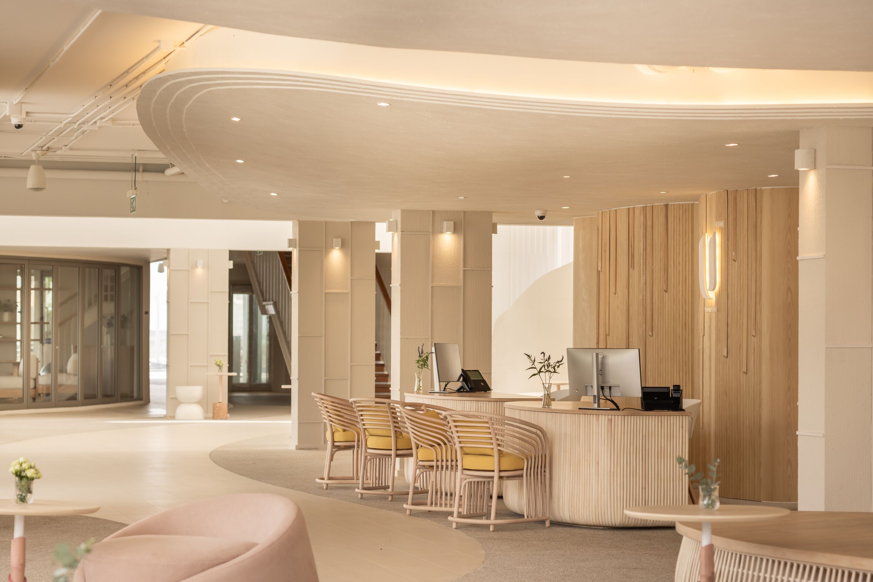 A modern reception area with a curved reception desk, seating with yellow cushions, and a clean, minimalist design.