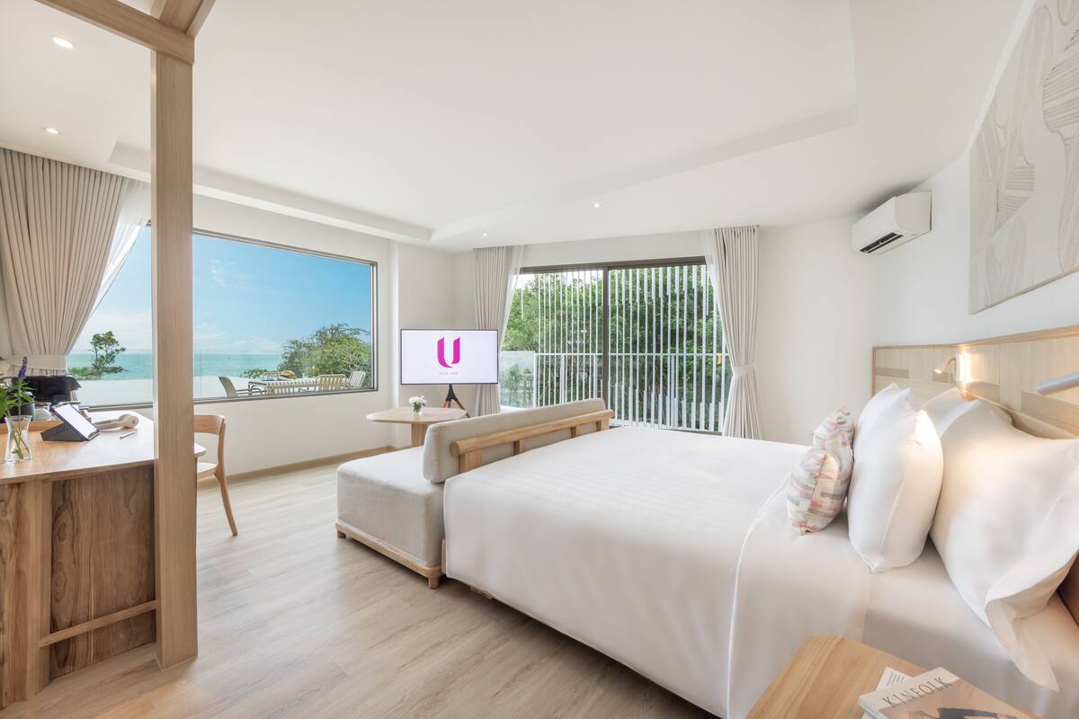 Une chambre d’hôtel moderne avec un grand lit, un bureau et une télévision.