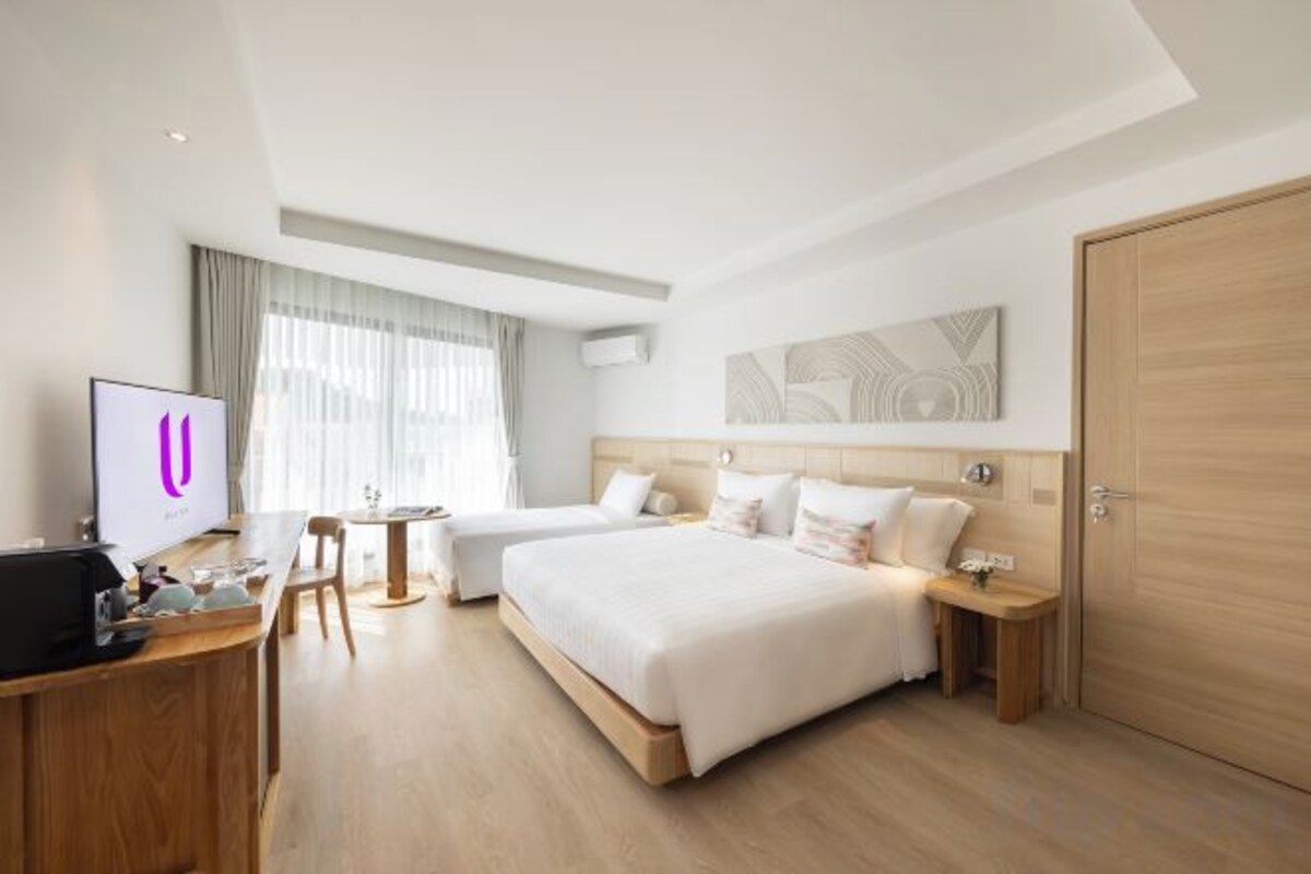 A hotel room with a bed, a desk, a TV, and a wardrobe.