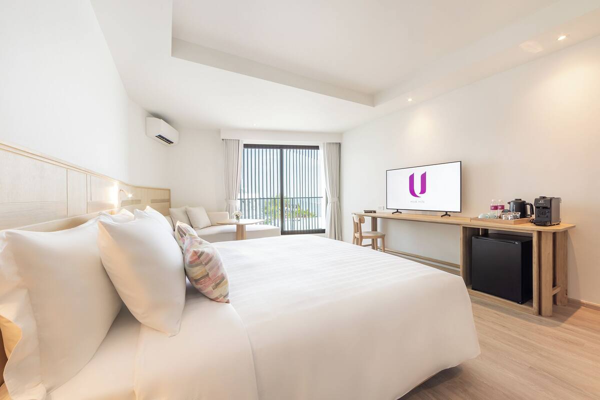 Une chambre d’hôtel avec un grand lit, un bureau avec un ordinateur, une machine à café et une télévision.