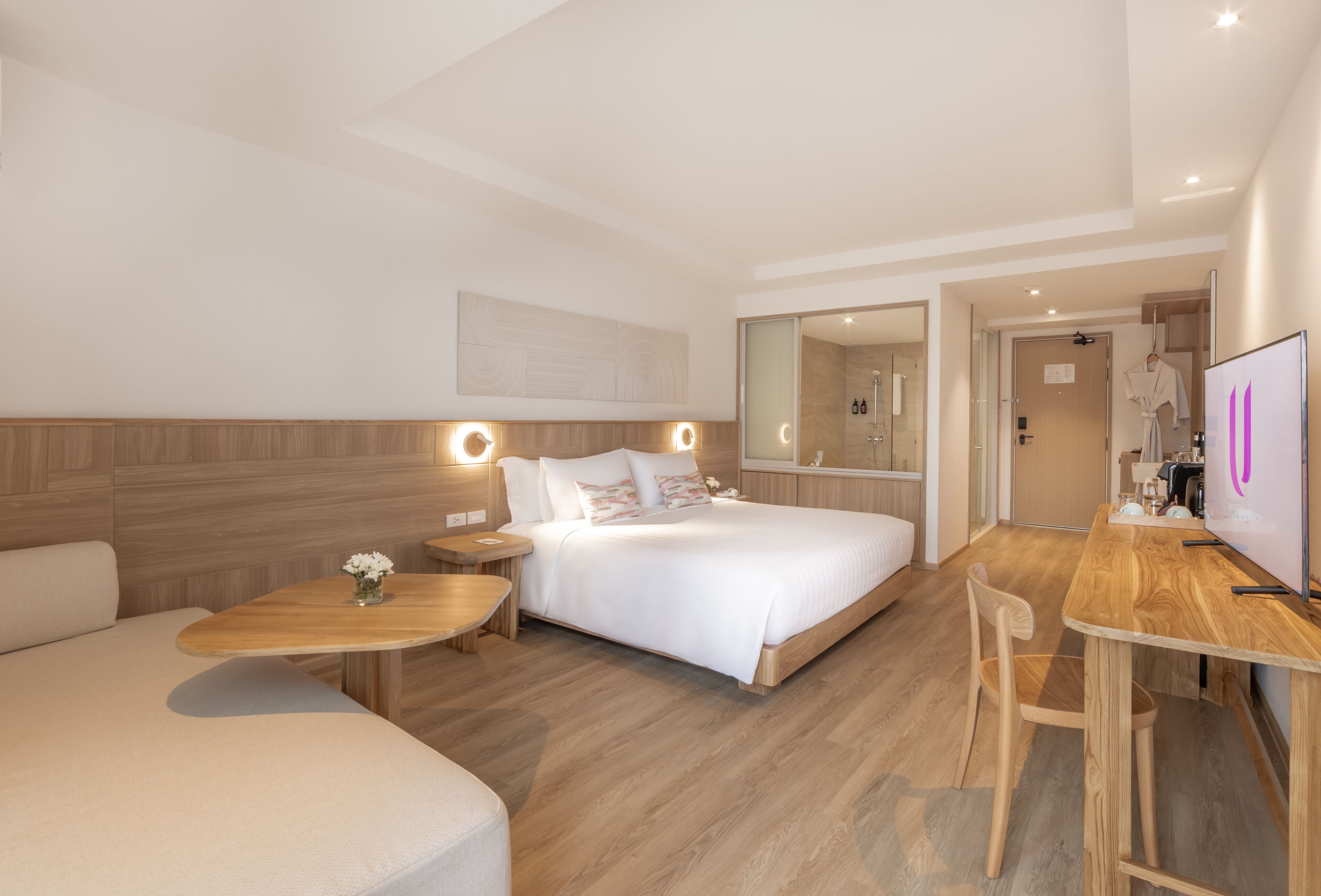 Una habitación de hotel moderna con una cama, un escritorio, una silla, una mesita con un florero y un espejo.