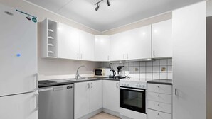 A modern kitchen with white cabinets, a stainless steel refrigerator, a microwave, a stove, and a sink. - Lovly 3 Bedroom Apartment With the View of Aurora (Tromsø)