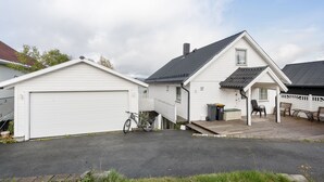 A white house with a garage, a covered porch, and a bicycle parked outside. - Lovly 3 Bedroom Apartment With the View of Aurora (Tromsø)