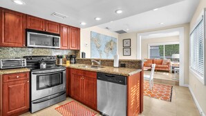 Una cocina moderna con encimeras de granito, electrodomésticos de acero inoxidable y armarios de madera.