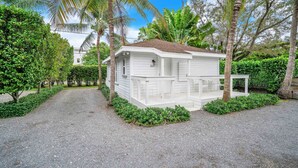 A white building with a number 3330, surrounded by lush greenery and palm trees.