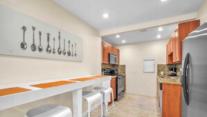 Una cocina moderna con barra blanca, electrodomésticos de acero inoxidable y armarios de madera.