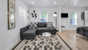 A modern living room with a grey sectional sofa, a round coffee table, and a patterned rug. - Tropical Grove Bay 1/1 | Newly Renovated Escape (Miami)