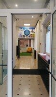 Un hall de hotel con mostrador de recepción, un sillón amarillo y una pared con un cartel de bienvenida.