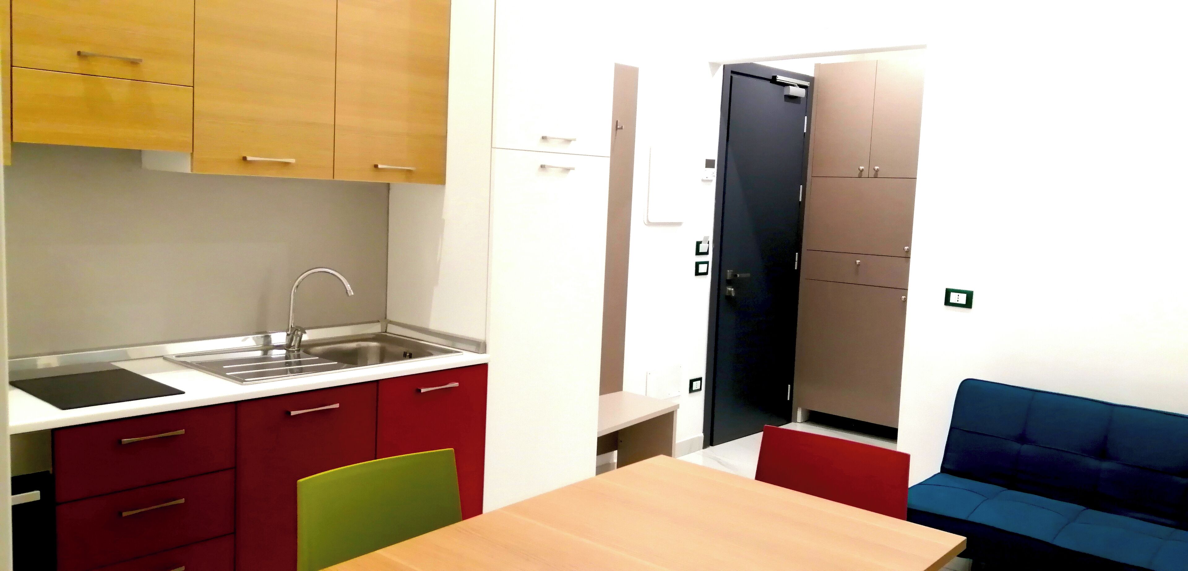 A compact kitchen with a sink, cabinets, and a dining area with a table and chairs.