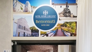 A hotel lobby with a reception desk, a green carpet, and a yellow armchair. - HOTEL HOUSE GARGANO (San Giovanni Rotondo)