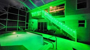 A swimming pool area with a glass ceiling, a staircase, and a balcony. - Capri Charm Remodeled Oasis w/ Heated Pool-Kayaks (Naples)