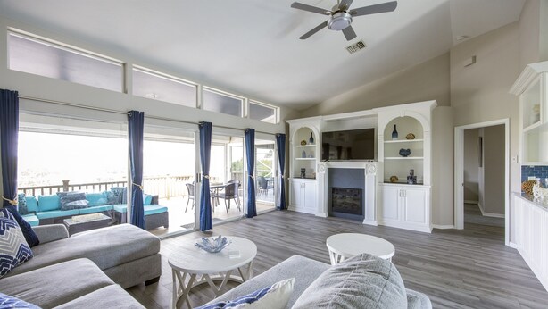 A spacious living area with a sofa set, a fireplace, and a view of the outdoors. - Capri Charm Remodeled Oasis w/ Heated Pool-Kayaks (Naples)