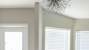 A dining area with a wooden table, grey upholstered chairs, and a decorative white cushion. - Capri Charm Remodeled Oasis w/ Heated Pool-Kayaks (Naples)