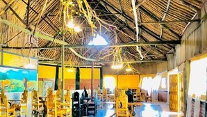 Une salle à manger spacieuse avec de hauts plafonds et un toit de chaume, agrémentée de chaises et de tables en bois.