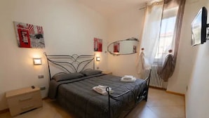 Een slaapkamer met een bed, nachtkastjes, een radiator en kunst aan de wanden.