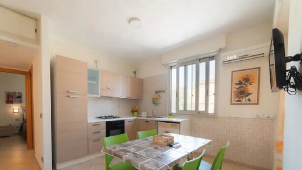 Een compacte keuken met een eethoek, met een tafel en stoelen, een fornuis en een spoelbak.