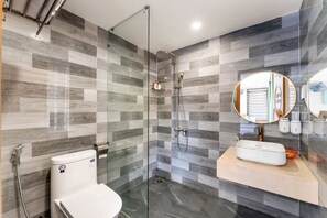 A modern bathroom with a glass-enclosed shower, a white sink, and a mirror with a circular frame. - The Linh Seaside Villa Hoi An (Da Nang)