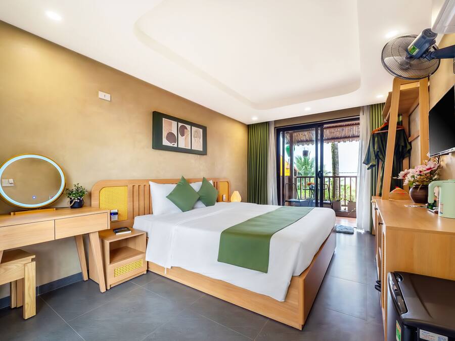 A hotel room with a bed, a desk, a chair, a TV, and a window with a view of the outdoors.