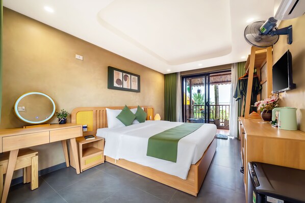 A hotel room with a bed, a desk, a chair, a TV, and a window with a view of the outdoors. - The Linh Seaside Villa Hoi An (Da Nang)