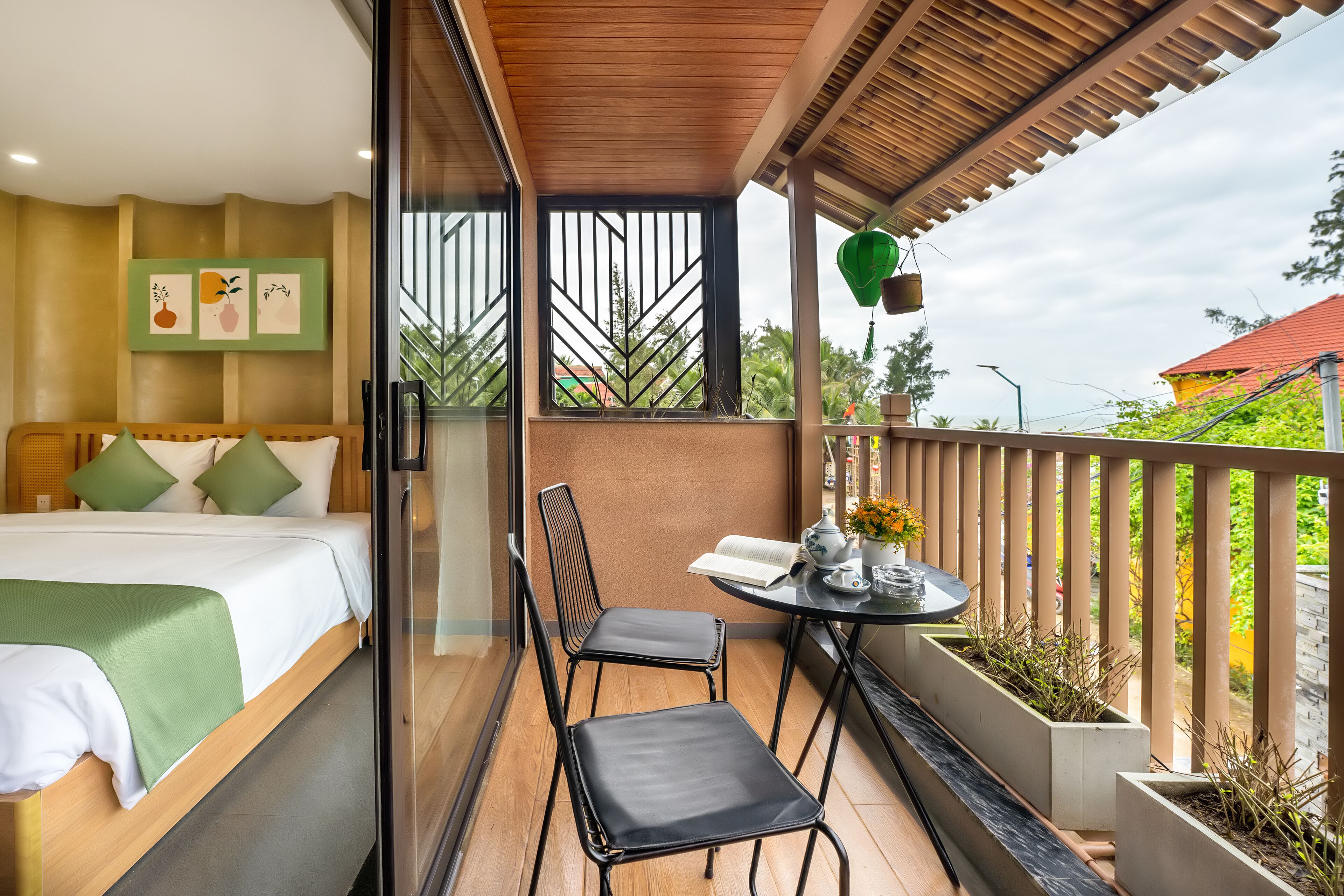 Un balcón con cama, dos sillas, una mesa y vistas a zonas verdes.