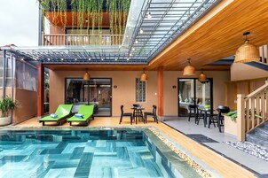 Un hotel moderno con piscina en la azotea, mobiliario exterior y techo de cristal.