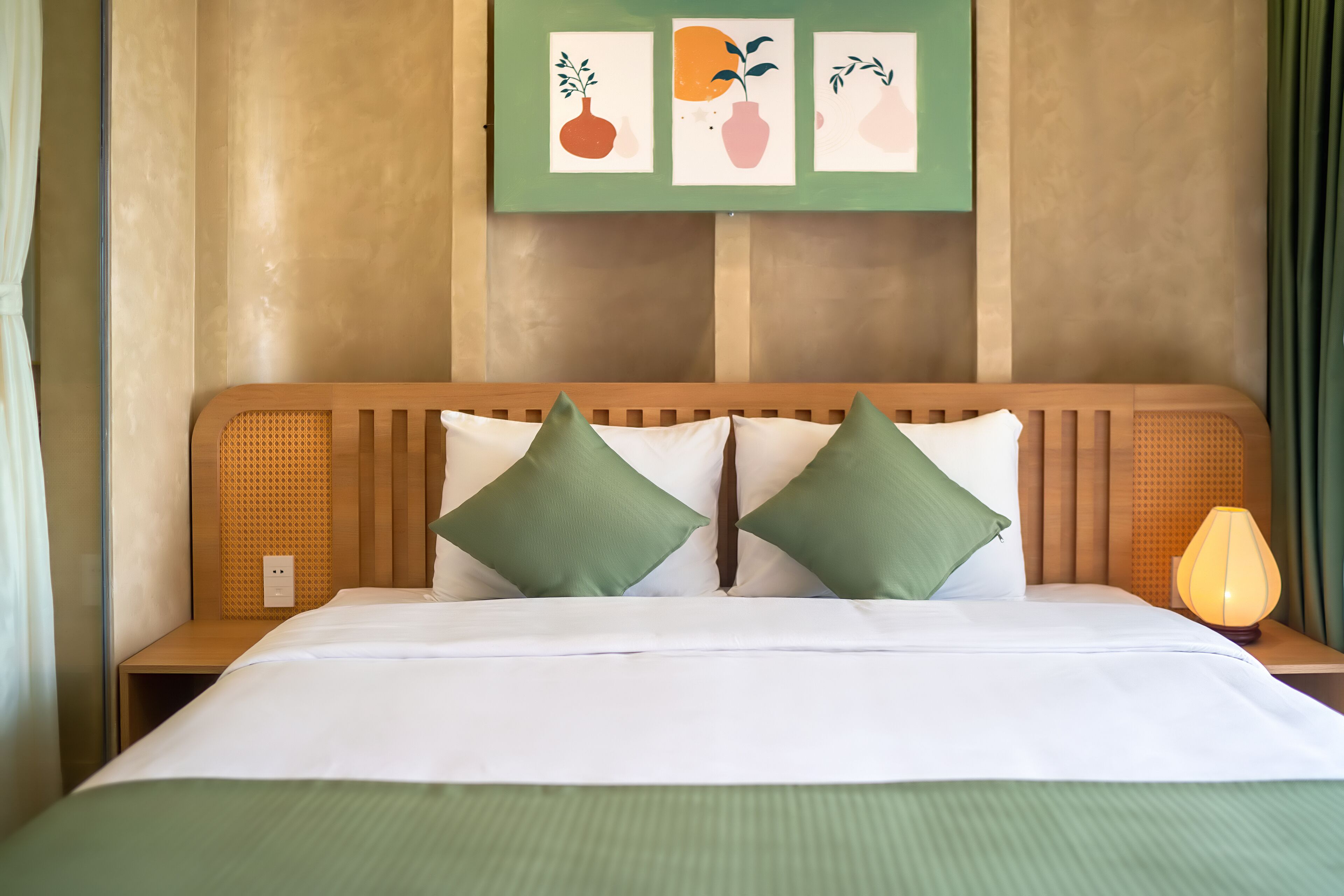 A neatly made bed with green bedding, two green pillows, and a wooden headboard.