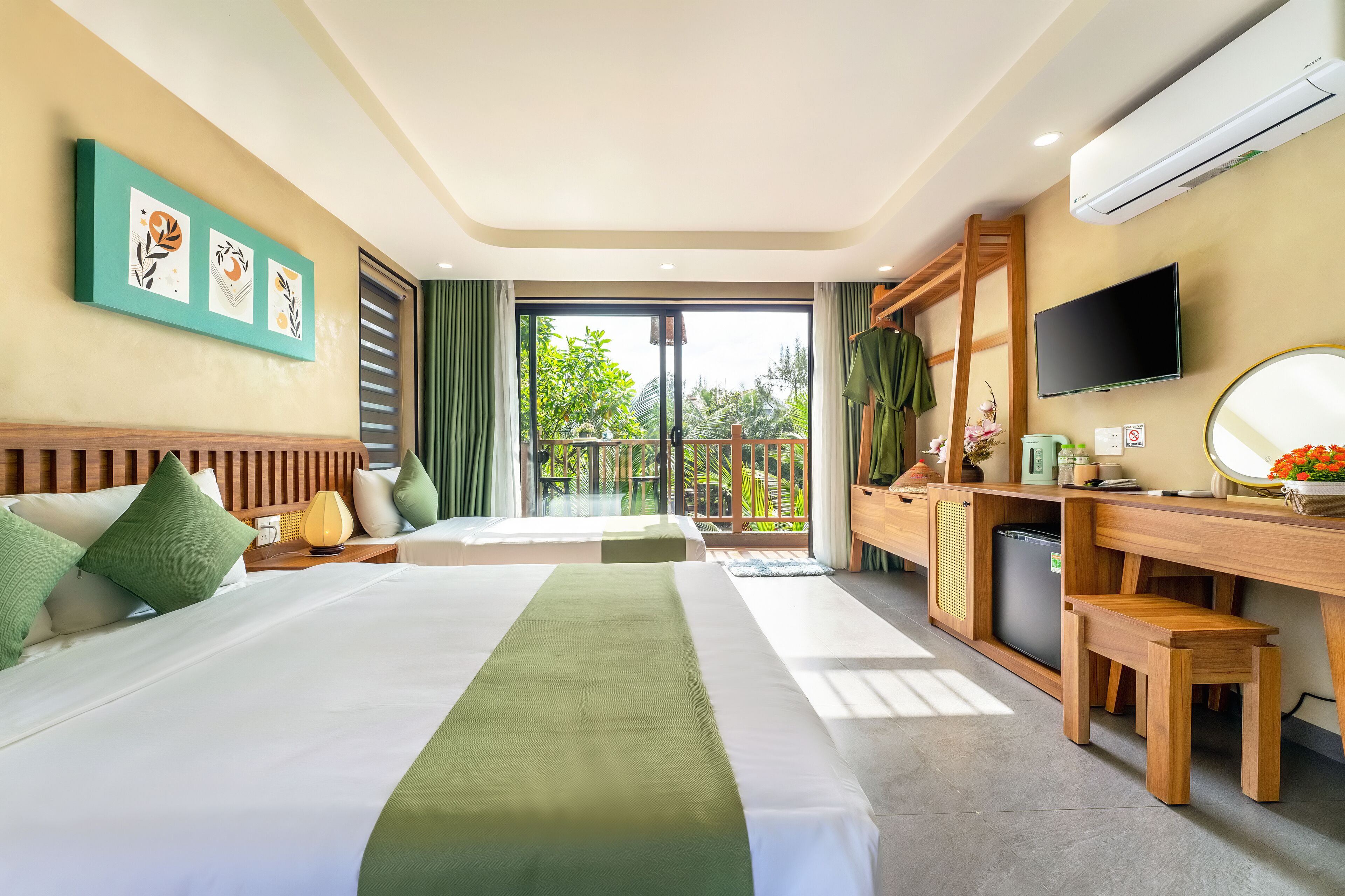 A hotel room with two beds, a desk, a TV, and a balcony with a view of greenery.