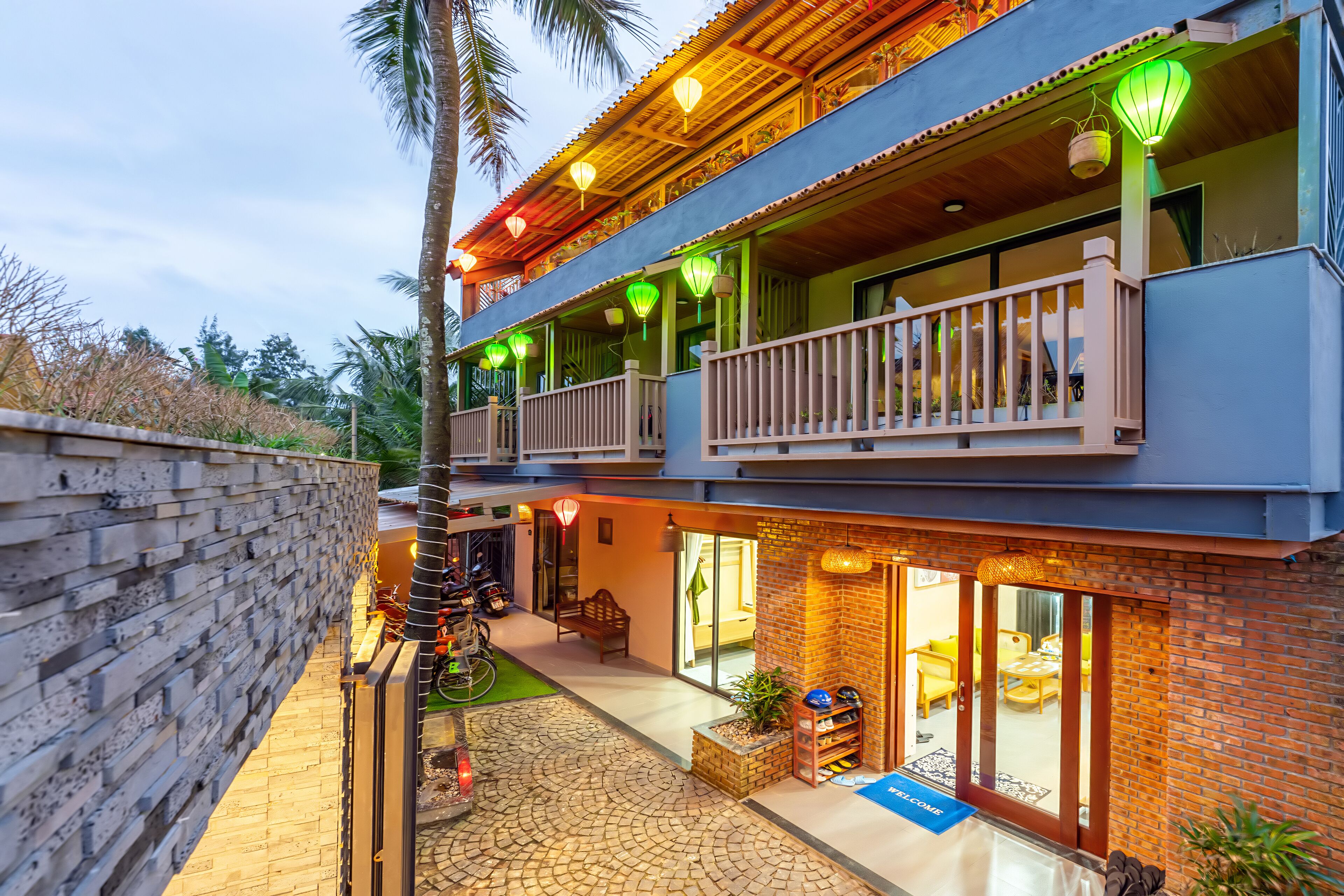 A two-story building with a balcony, outdoor seating area, and a brick facade.