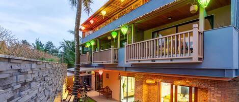 A two-story building with a balcony, outdoor seating area, and a brick facade.