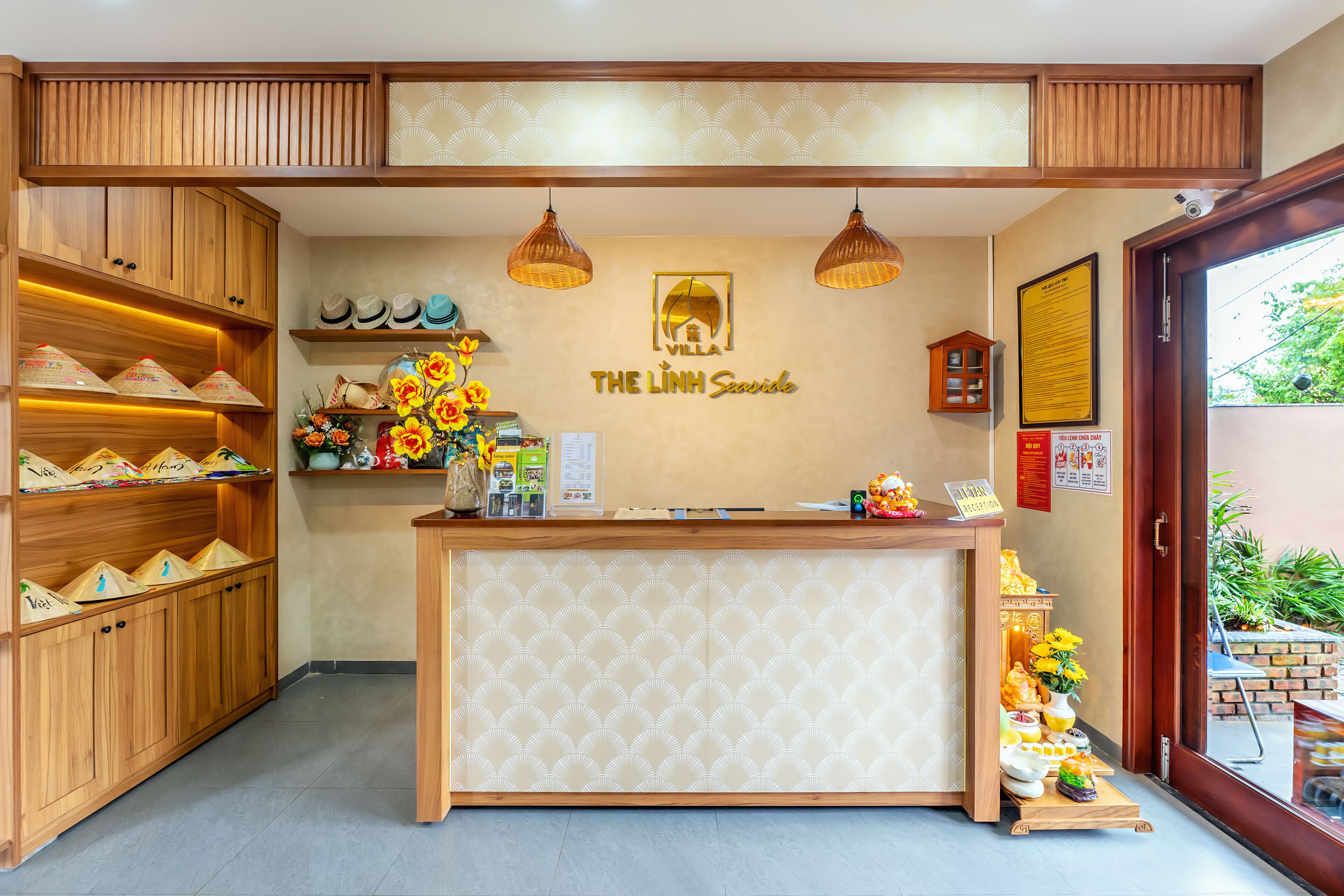 A reception desk with a wooden finish, a wall-mounted sign reading "The Linh Seaside," and a small shrine with offerings.