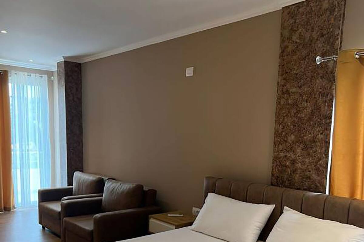 A hotel room with a large bed, a sofa, and a nightstand.