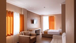 Ein modernes Hotelzimmer mit einer Couch, einem Bett, einem an der Wand befestigten Fernseher und Holzboden.