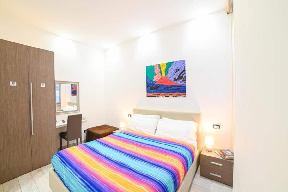 Ein Schlafzimmer mit Bett, Schreibtisch, Kleiderschrank und einem Bild an der Wand.
