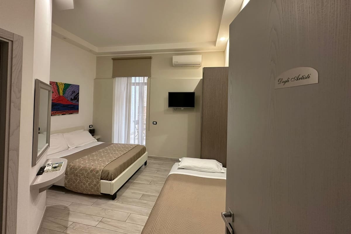 Ein Hotelzimmer mit einem Bett, einem Fernseher, einem Gemälde an der Wand und einem Schild mit der Aufschrift "Degli Artisti".