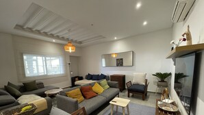 Una sala de estar moderna con un sofá gris, una silla de madera, una mesita y una planta en maceta.