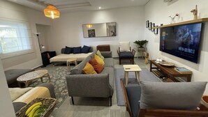 Una sala de estar moderna con un sofá, sillones, un televisor y un comedor.
