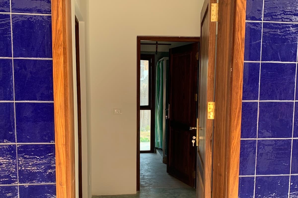 Un pasillo con paredes de azulejos azules y un marco de puerta de madera.