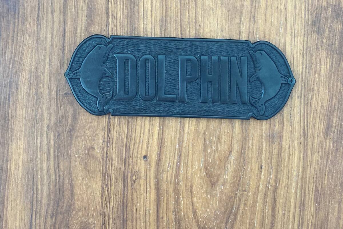 Una superficie de madera con una placa con forma de delfín.