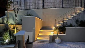 A modern outdoor staircase with steps leading up to a building, surrounded by gravel and potted plants. - Large 2-room apartment with panoramic sea view (Rayol-Canadel-sur-Mer)